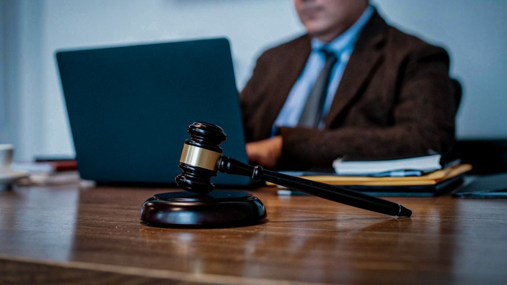 Ein Mann arbeitet an einem Laptop, vor ihm liegt ein Richterhammer.