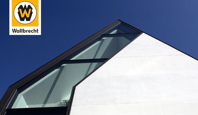 Die Spitze eines modernen Gebäudes in der Bildmitte. Oben links ist das Logo der Wilhelm Wallbrecht GmbH & Co. KG.