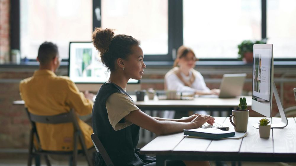 Eine Frau, die in einem Büro sitzt und an einem Rechner arbeitet.