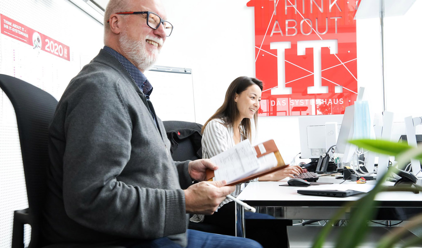 Ein Mitarbeiter der think about IT lächelt und hält ein Buch in der Hand.