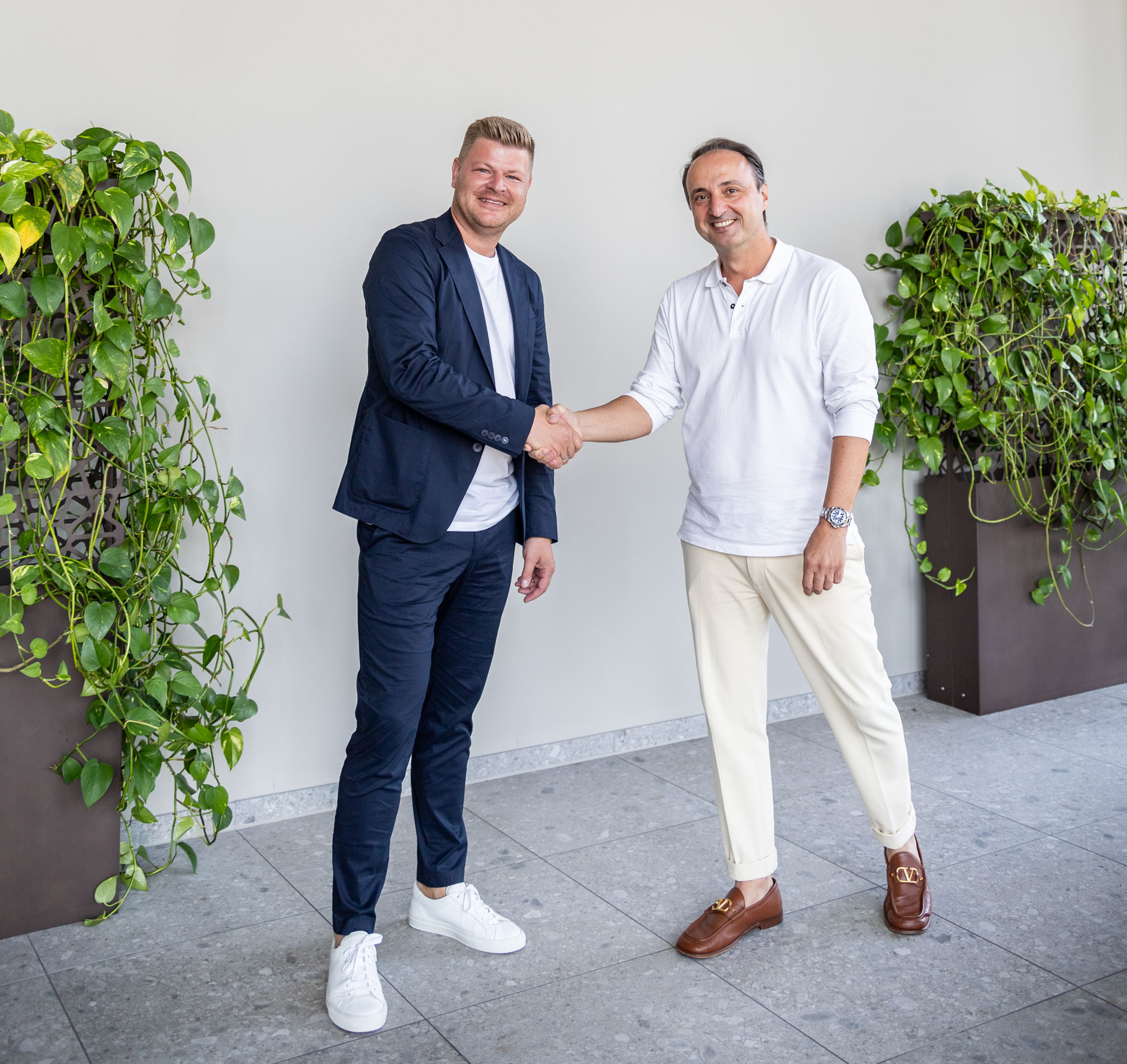 COO Daniel Gade und CEO Peter Rados schütteln sich lächelnd die Hand.