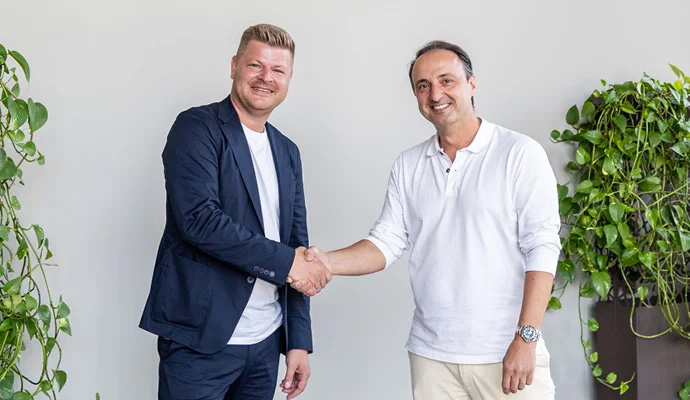 COO Daniel Gade und CEO Peter Rados schütteln sich lächelnd die Hand.