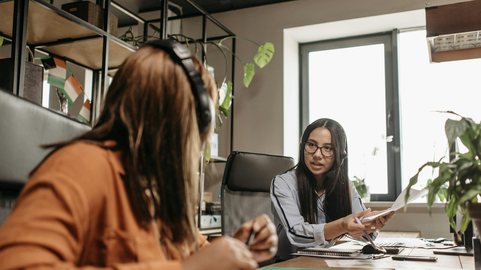 Zwei Mitarbeiterinnen, die sich am Arbeitsplatz austauschen.