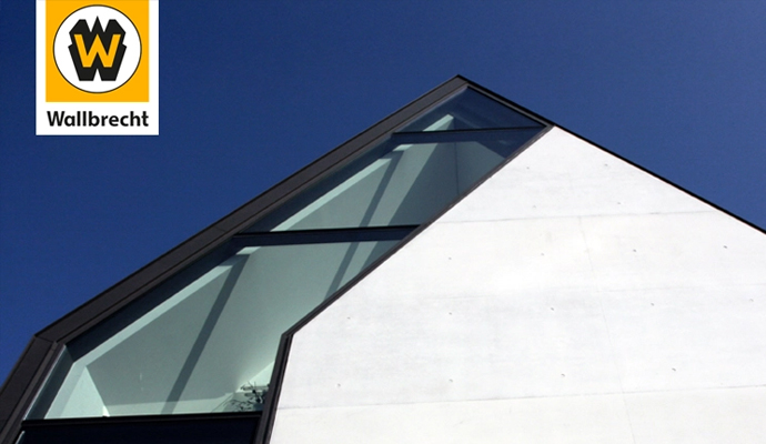 Die Spitze eines modernen Gebäudes in der Bildmitte. Oben links ist das Logo der Wilhelm Wallbrecht GmbH & Co. KG.