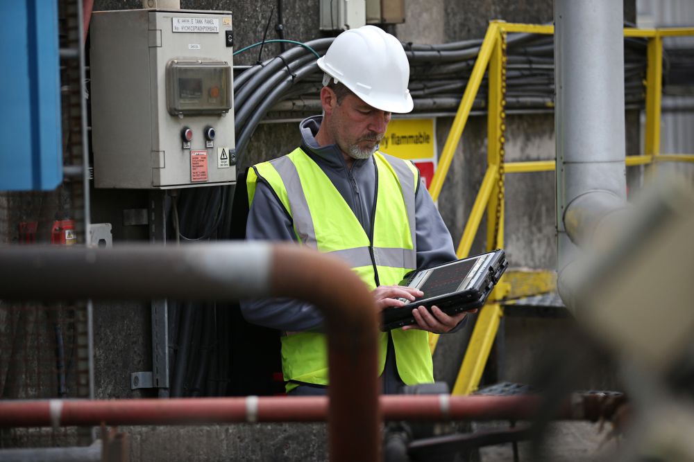 Ein Mann in Bauarbeiter Ausrüstung bedient ein Toughbook.