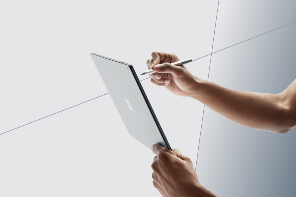 Zwei Arme, die ein Tablet halten und mit einem Stift darauf schreiben.