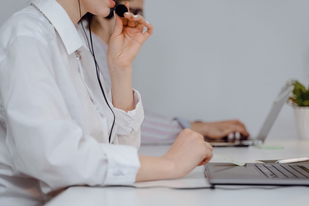 Eine Frau führt ein Telefonat über ihr Headset am Arbeitsplatz.
